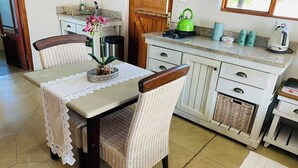 Cozinha com mesa de jantar, cadeiras e janela.