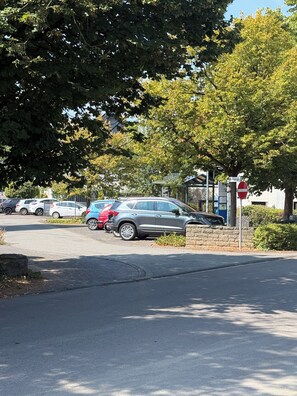 Ein Parkplatz mit mehreren Autos, einem Verbotsschild und einem Gebäude mit Gründach im Hintergrund.