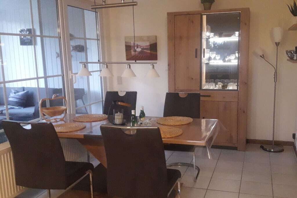 Un comedor con una mesa de madera, sillas negras y un aparador de vidrio.