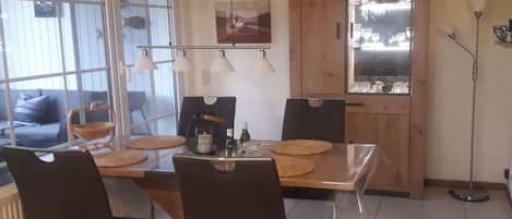 A dining area with a wooden table, black chairs, and a glass cabinet.