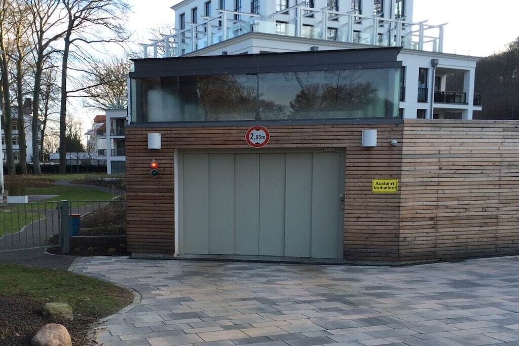 Un edificio moderno con una puerta de garaje grande, un cartel de no estacionamiento y una señal que indica un área de estacionamiento.