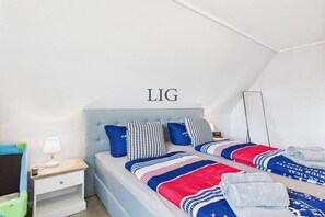 Ein Schlafzimmer mit zwei Betten, einem Nachttisch, einer Lampe und einem an der Wand befestigten Spiegel.