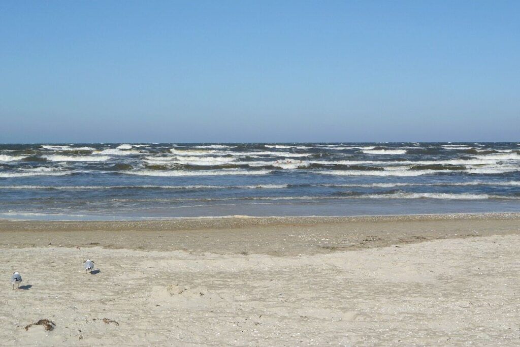 A beach with waves and a clear sky.