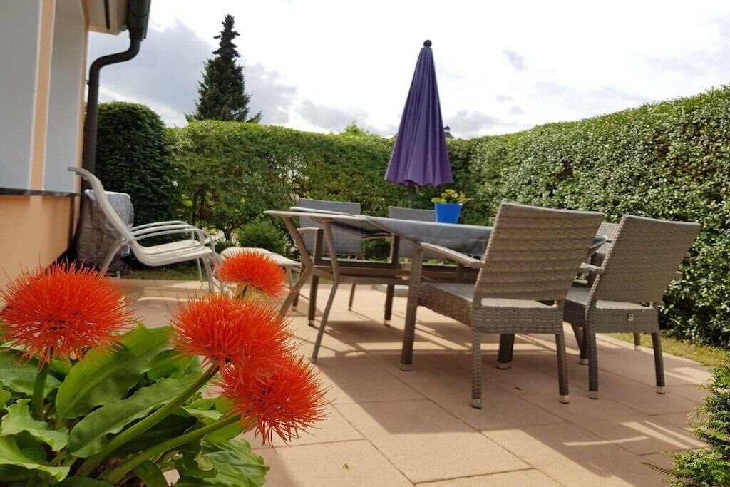 Une terrasse extérieure aménagée avec des meubles en osier, une table et des chaises.