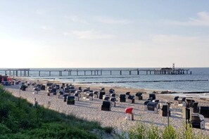 Ein Strand mit vielen Liegestühlen und einem Steg, der ins Wasser ragt.