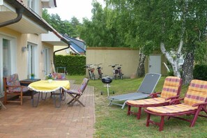 A patio with a table and chairs, a grill, and a lawn chair area. - Villa Florenz Ground Floor (Koserow)
