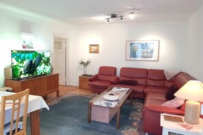 Ein Wohnzimmer mit einer Couch, einem Couchtisch, einem Fernseher und einer Lampe.