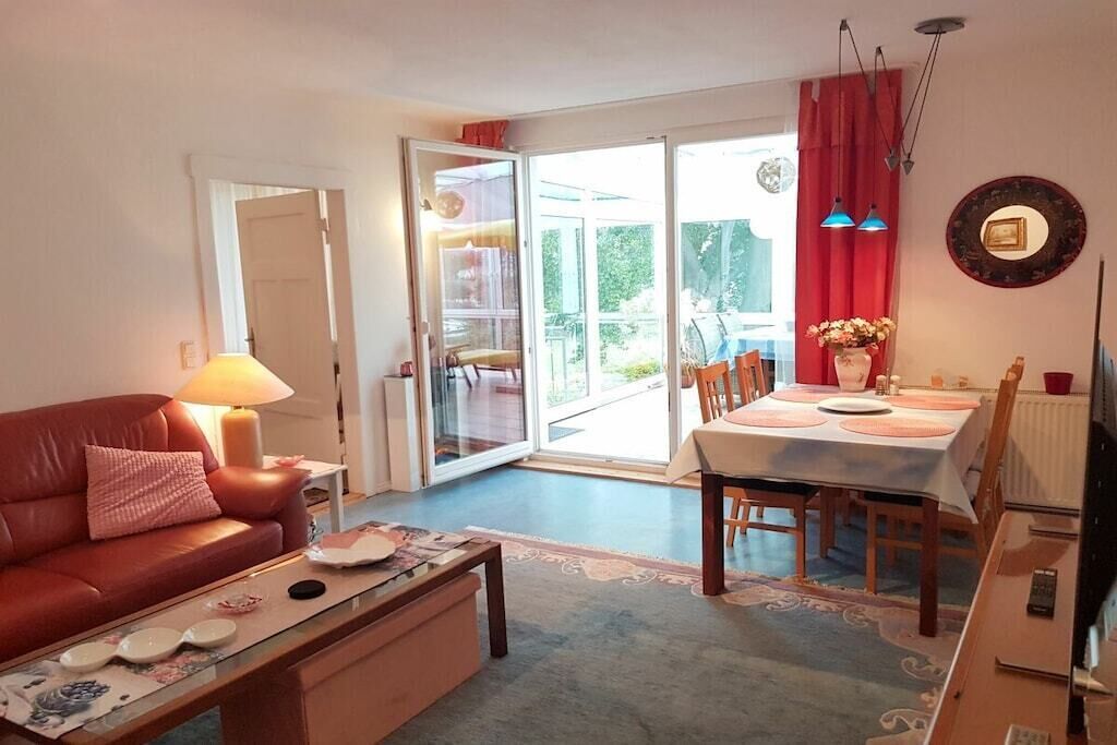 A living room with a sofa, coffee table, and dining area with chairs and a table.