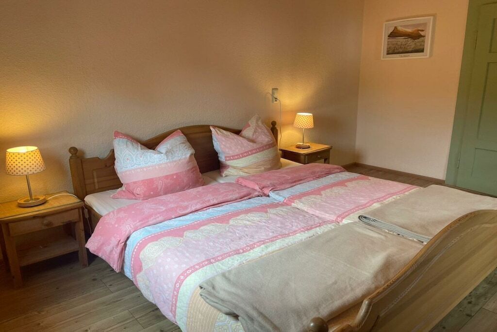A bedroom with a bed, two bedside tables, and lamps.