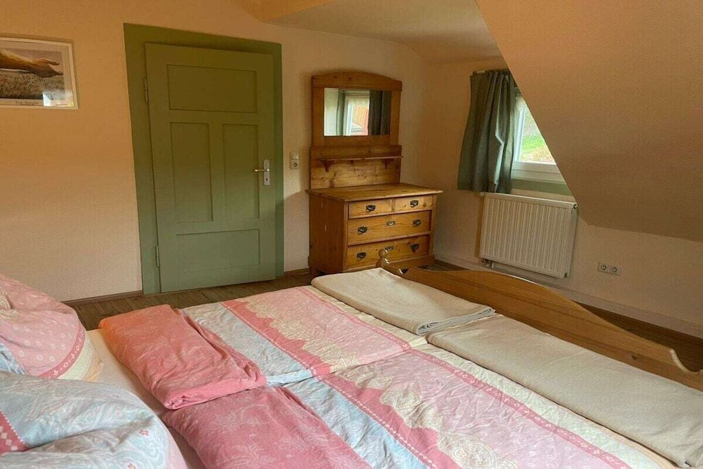 Ein Schlafzimmer mit einem Bett, einem Schminktisch, einer Tür und einem Fenster.