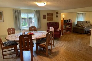 A dining area with a round wooden table and chairs, a red armchair, and a bookshelf. - Holiday home at Krechenbach (Eckarts)