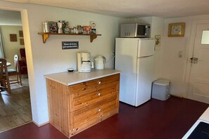 A compact kitchen with a wooden cabinet, a white refrigerator, a microwave, and a coffee maker. - Holiday home at Krechenbach (Eckarts)