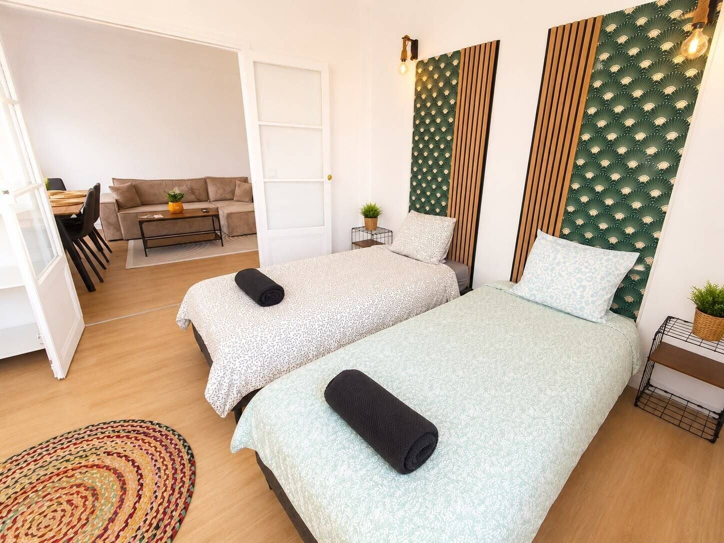 A hotel room with two beds, a sofa, a dining area, and a view of the outside.
