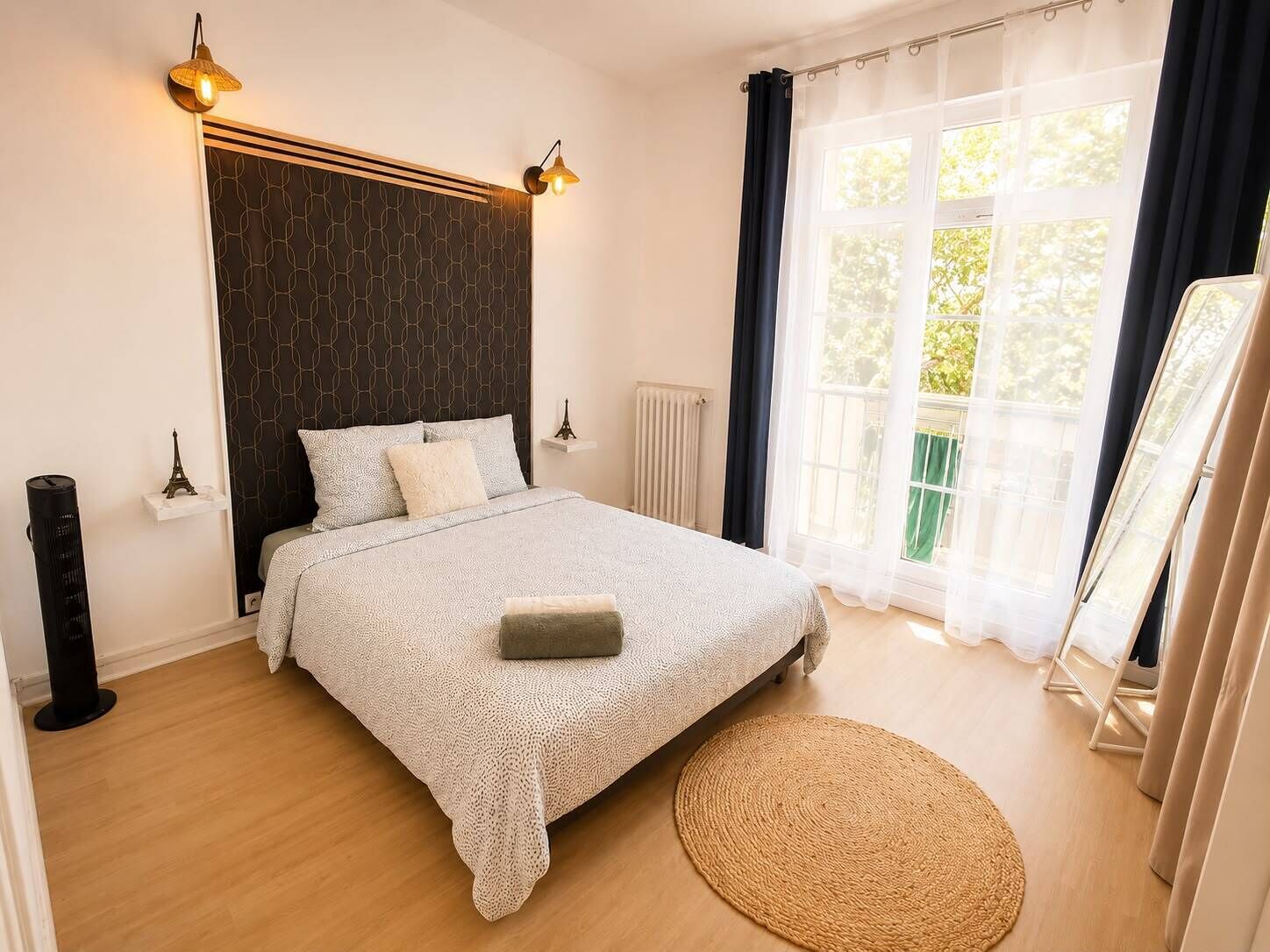 Une chambre à coucher avec un lit, des lampes de chevet, un radiateur, un tapis rond et une fenêtre avec des rideaux.