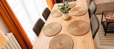 A dining area with a wooden table, woven placemats, and grey upholstered chairs.
