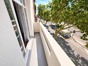 Ein Balkon mit Blick auf eine Straße und einen Baum.