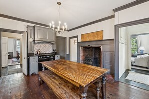 Un'ampia cucina con un grande tavolo di legno, piano cottura integrato e camino.