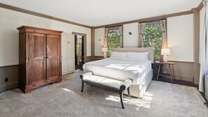A bedroom with a large bed, a wooden wardrobe, and a bench.