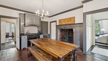 A spacious kitchen with a large wooden table, a built-in stove, and a fireplace.