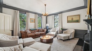 A spacious living room with a brown leather sofa, beige armchairs, and a round coffee table.