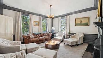 A spacious living room with a brown leather sofa, beige armchairs, and a round coffee table.