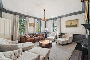 A spacious living room with a brown leather sofa, beige armchairs, and a round coffee table.