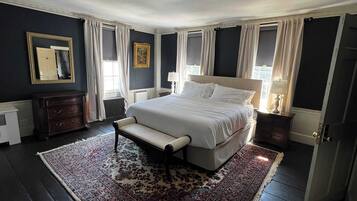 A bedroom with a large bed, a bench, a dresser, and a patterned rug.