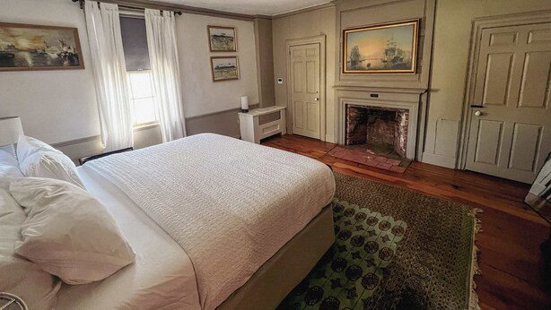 Une chambre d’hôtel avec un lit, une cheminée, une porte et un tableau au mur.