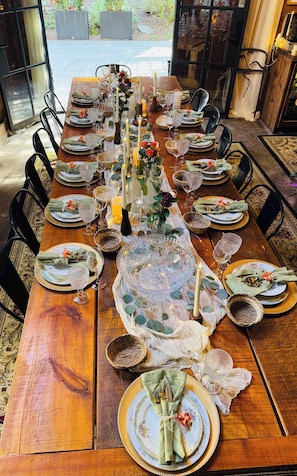 A long dining table set for a meal with multiple chairs, candles, and decorative centerpieces.
