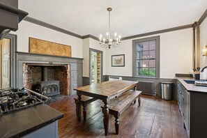 Una cucina con un tavolo di legno, una panca e un camino.