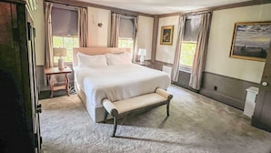A bedroom with a large bed, a bedside table, a chair, and a window.