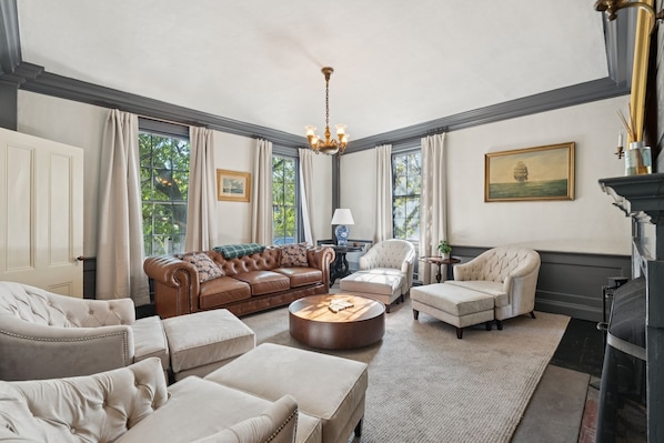 A spacious living room with a brown leather sofa, beige armchairs, and a round coffee table.