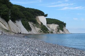 A pebbled beach with a rocky cliff and a clear sky. - 03, Residence Dünenstraße (Binz)