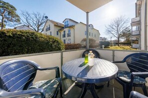 A balcony with a round table and two chairs, a bottle, and a glass. - 03, Residence Dünenstraße (Binz)