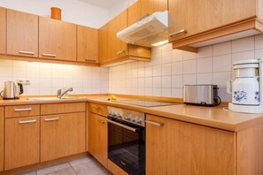 Een moderne keuken met houten kastjes, een inbouwoven, een koffiezetapparaat en een waterkoker.