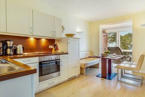 A compact kitchen with white cabinets, a built-in oven, and a coffee maker. - Dream time at Villa Freia (Binz)