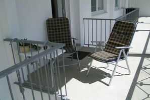 Two plaid chairs on a balcony with a metal railing, a potted plant, and a window. - Dream time at Villa Freia (Binz)