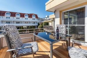 An outdoor balcony with a glass table and two patterned chairs. - Holiday apartment in Binz with swimming pool (Binz)