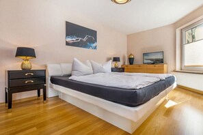A bedroom with a bed, bedside tables, a TV, and artwork on the wall. - Holiday apartment in Binz with swimming pool (Binz)