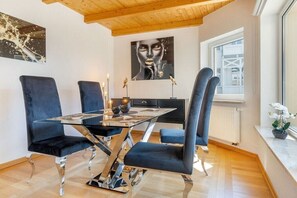 Ein stilvoller Essbereich mit einem Glastisch, blau gepolsterten Stühlen und Kunstwerken an den Wänden.