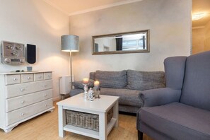 A modern living room with a grey sofa, white dresser, and a floor lamp. - 16, Residence Dünenstraße (Binz)