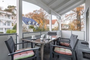 Ein überdachter Außenbereich mit Tisch und Stühlen, mit Blick auf eine Wohngegend.