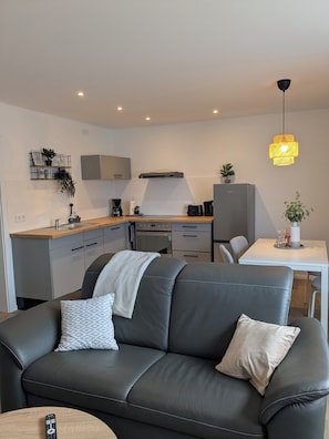 A modern kitchen with a built-in oven, a coffee machine, and a dining area with a table and chairs. - Vacation Rental in Ranzig - Old but Gold (Tauche)