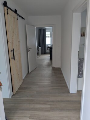 A hallway with a wooden sliding door, a dining area with a table and chairs, and a radiator. - Vacation Rental in Ranzig - Old but Gold (Tauche)