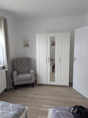 A bedroom with a bed, a wardrobe, a chair, and a radiator. - Vacation Rental in Ranzig - Old but Gold (Tauche)