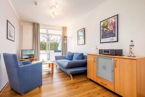 Ein modernes Wohnzimmer mit einer Couch, einem Sessel und einem Schrank mit Fernseher.