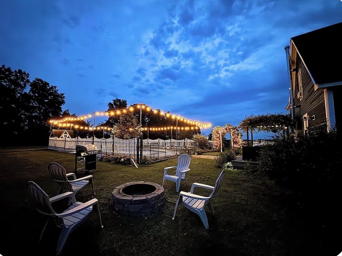 Een achtertuin met een vuurkorf, terrasstoelen en lichtjes.