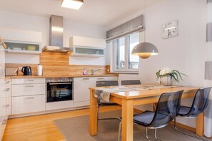 A modern kitchen with a dining area, including a table with chairs, a stove, and a window with a view. - "Island Pearl" in the Margarete Residence (Binz)