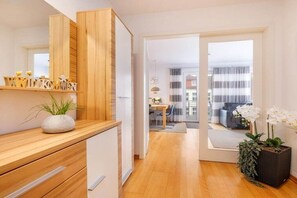A modern interior with a wooden counter, a potted plant, and a view into a living area through a glass door. - "Island Pearl" in the Margarete Residence (Binz)