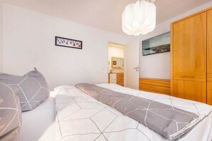 A bedroom with a bed, a wooden wardrobe, and a door leading to a bathroom. - "Island Pearl" in the Margarete Residence (Binz)